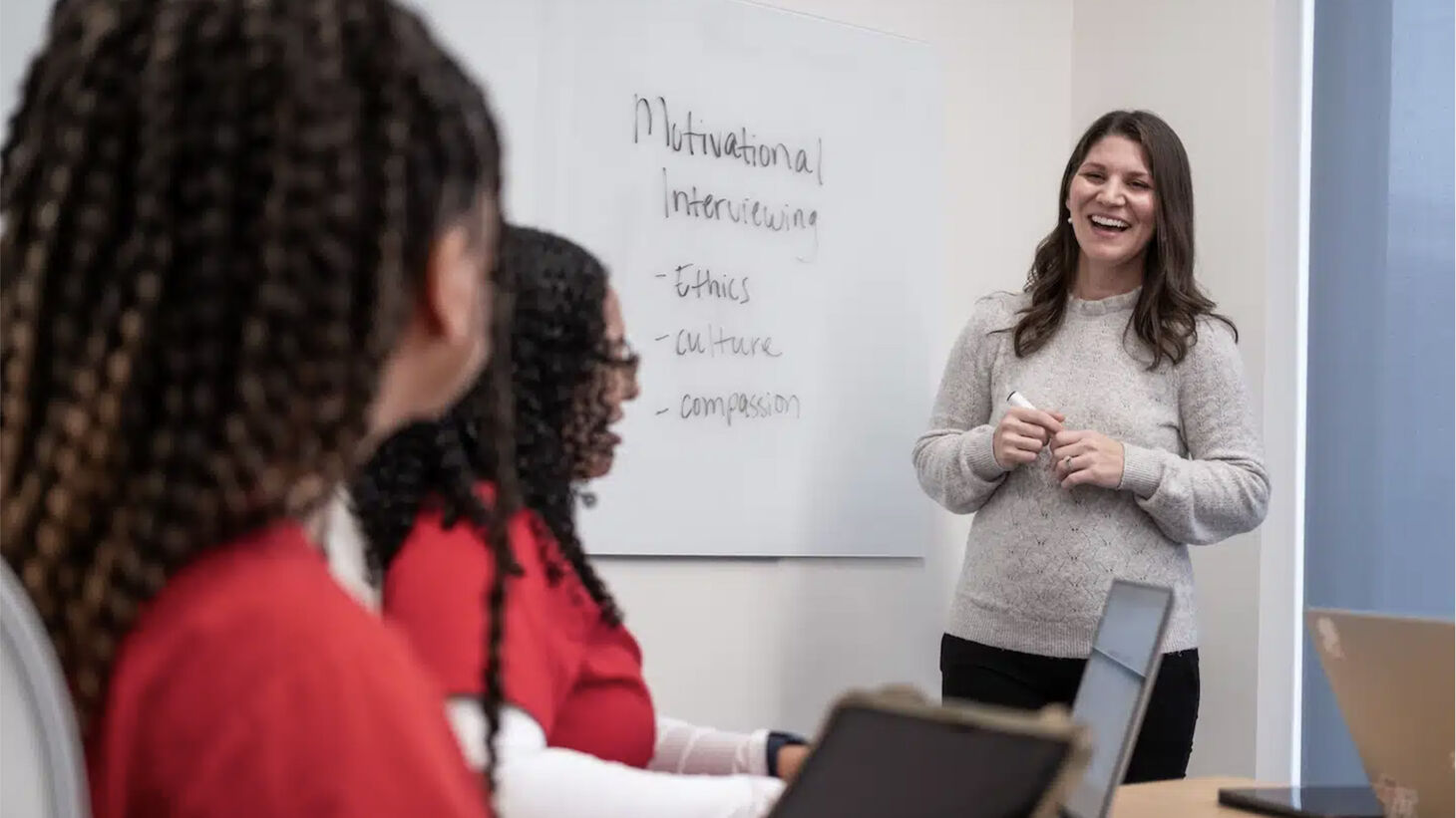 faculty member instructing nursing students in red scrubs