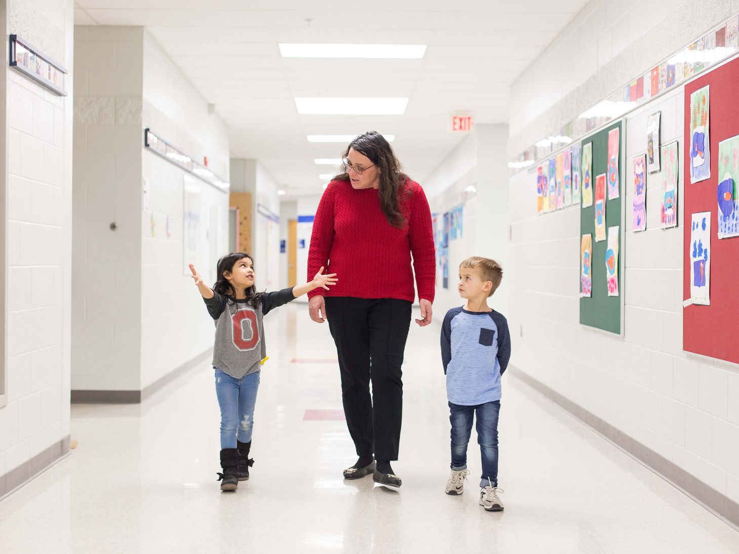 school nurse walking down hallway with two young students
