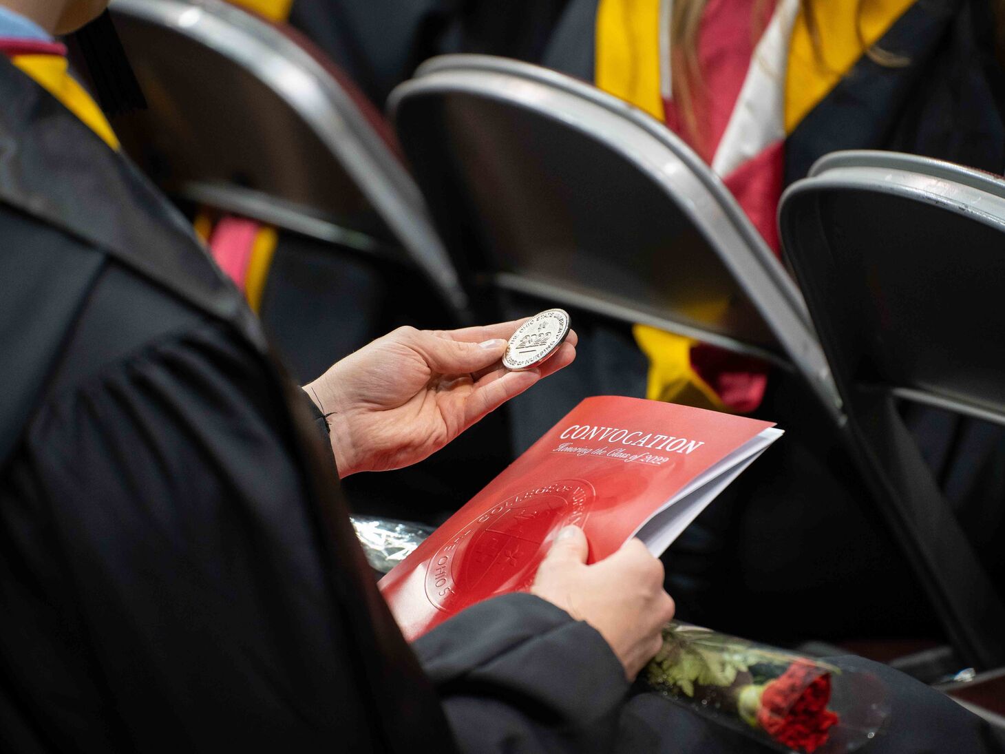 graduating student holding Convocation program and challenge coin