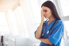 stressed nurse with hand on forehead