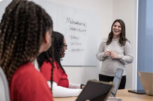 faculty member instructing nursing students in red scrubs