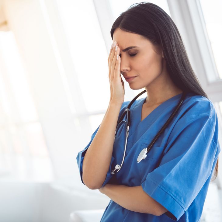 stressed nurse with hand on forehead