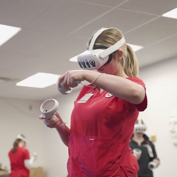 nursing student in red scrubs using virtual reality headset