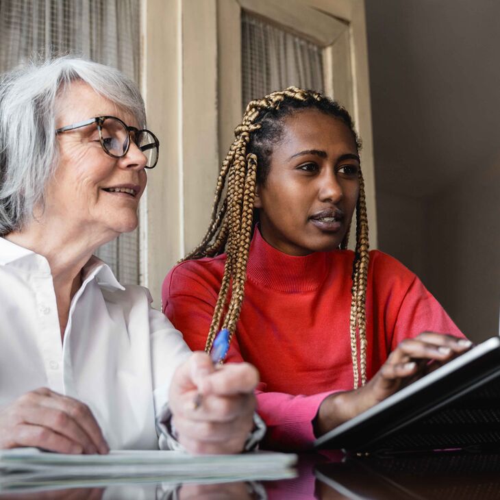 young woman helping older woman use a computer