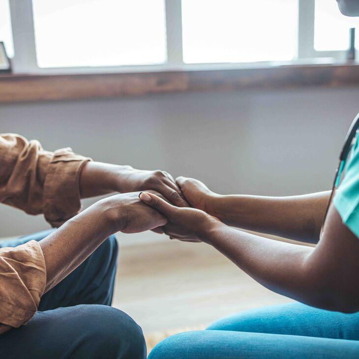 Close-up of home caregiver and senior man holding hands