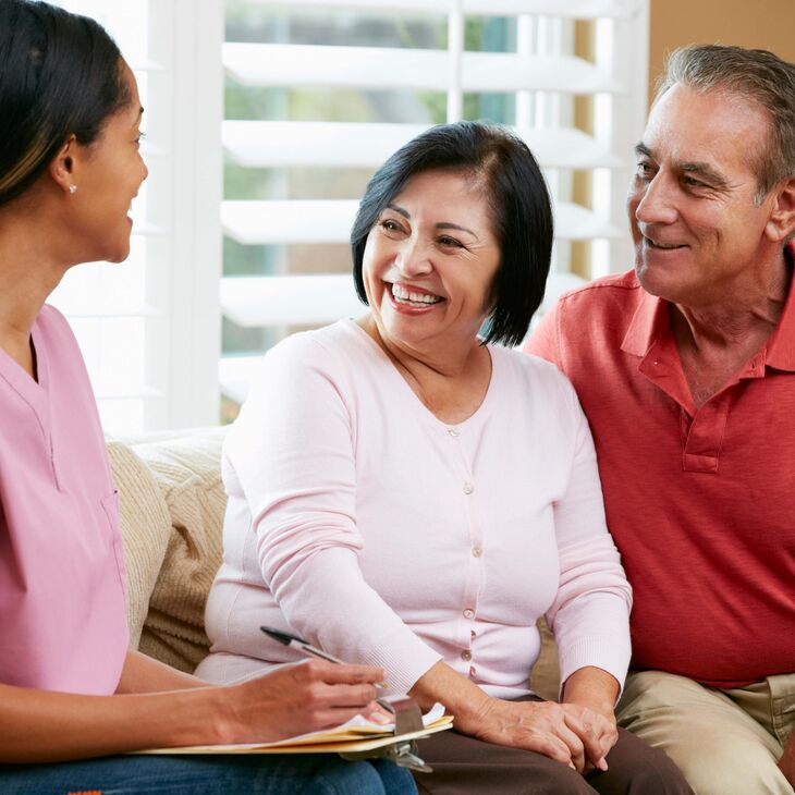 Nurse and elderly couple sitting together talking