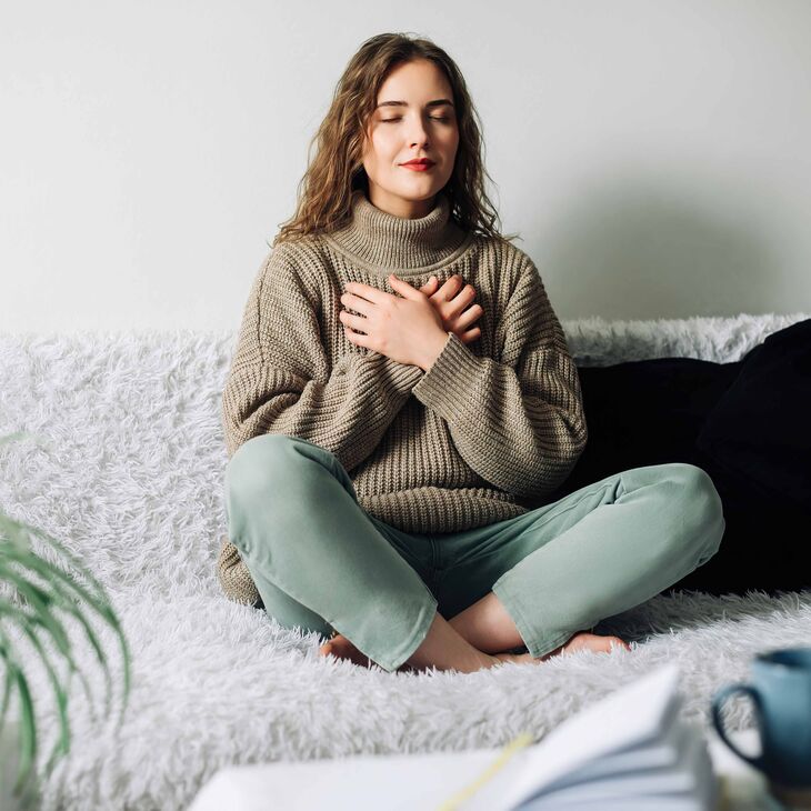 Caucasian woman sitting on couch practicing deep breathing