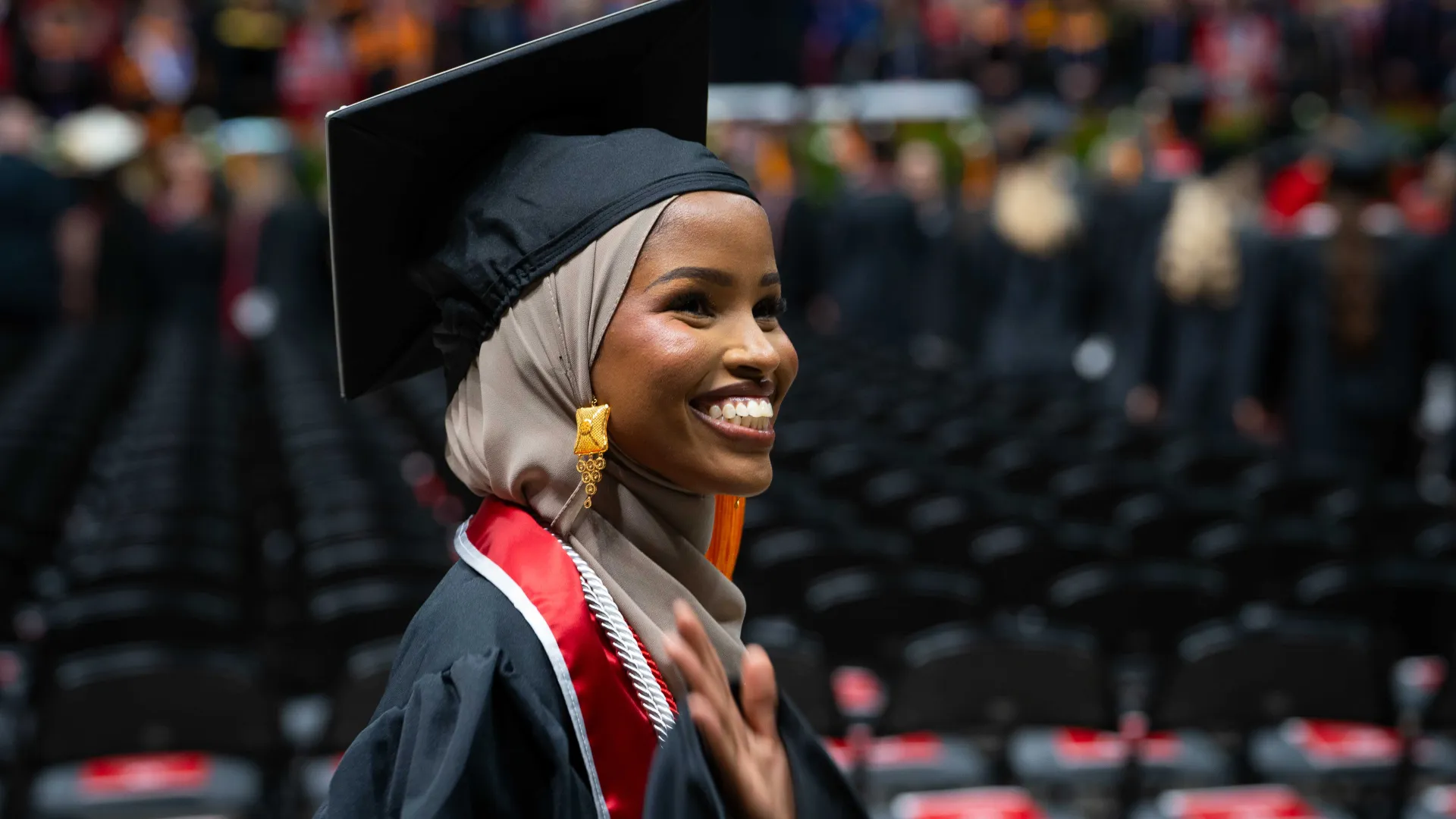 nursing student in graduation regalia waving to family at Convocation ceremony