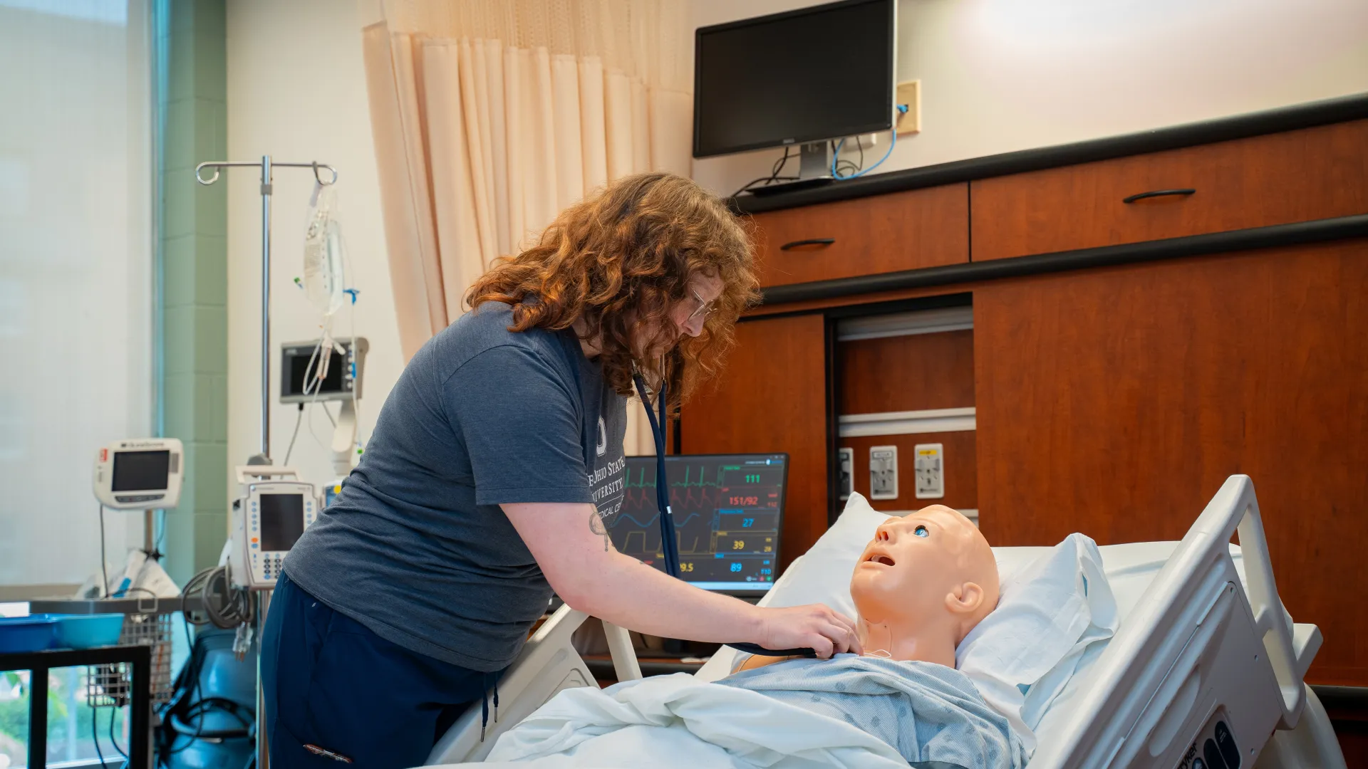 student using stethoscope on nursing mannequin in simulation lab