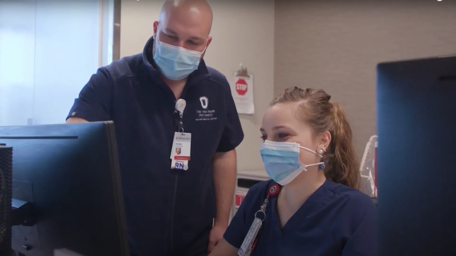 male and female nurse wearing face masks collaborating at computer
