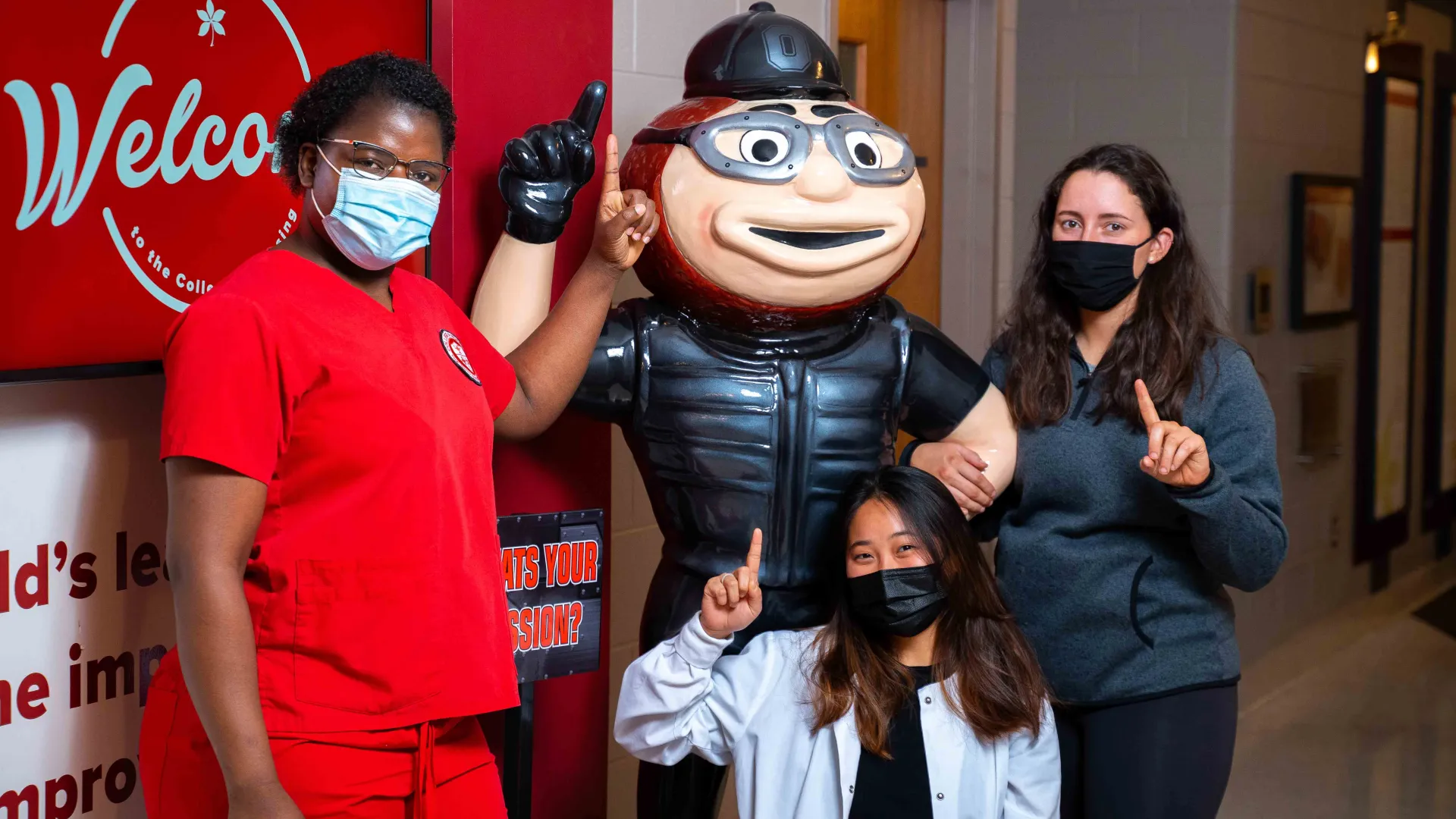 Carolyn Zhang, Monicah Karera and Audrey Robinson posing with a Brutus statue