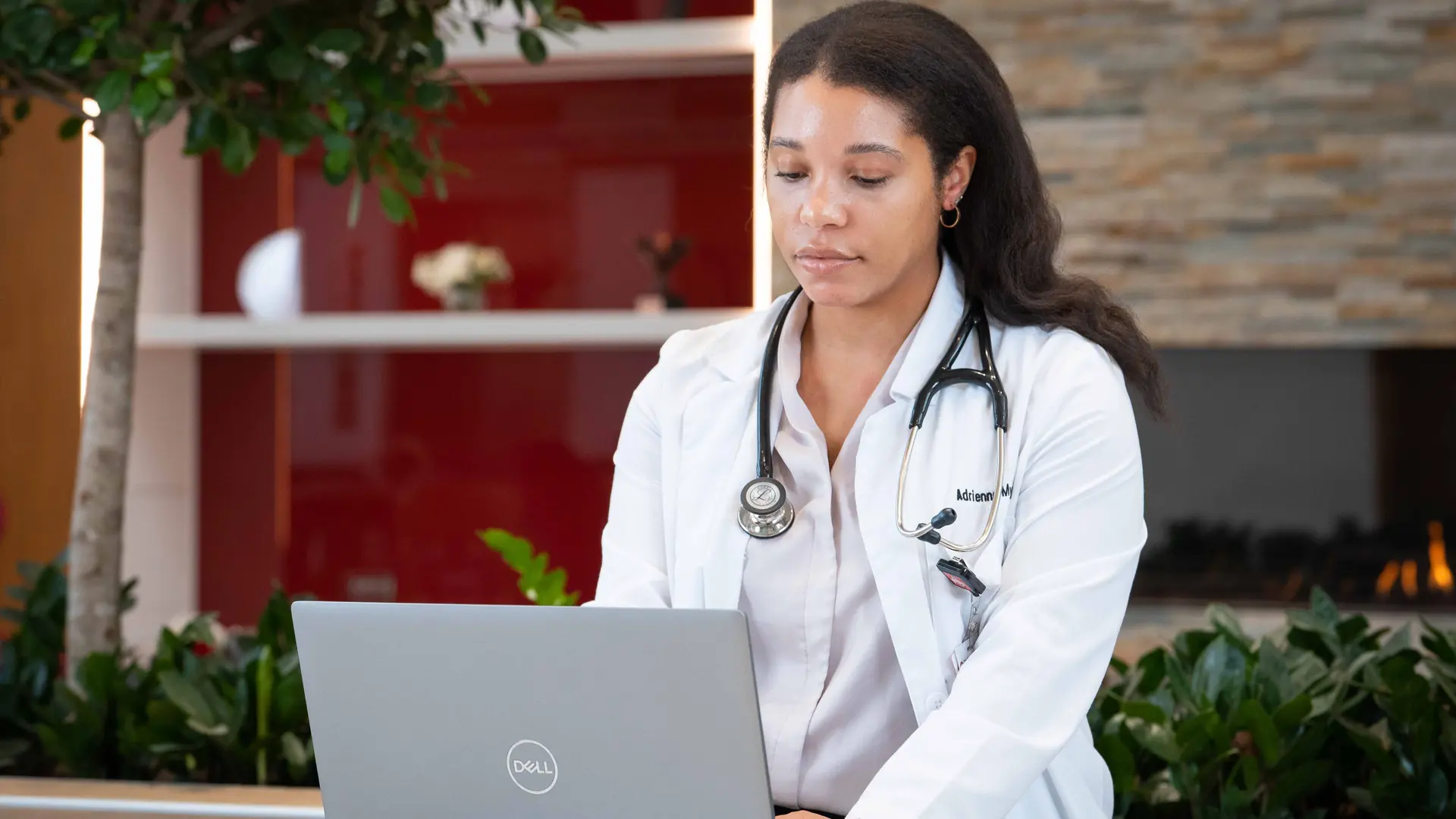 student in white coat works on laptop